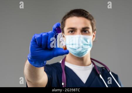 un giovane scienziato indaga un esame del sangue per il coronavirus. Diagnostica 2019-ncov. Risultato positivo del test del sangue per covid 19. Medico caucasico con un b Foto Stock