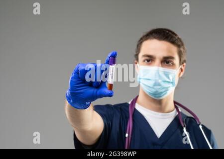 un giovane scienziato indaga un esame del sangue per il coronavirus. Diagnostica 2019-ncov. Risultato positivo del test del sangue per covid 19. Medico caucasico con un b Foto Stock