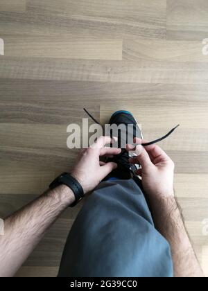 uomo che lega i lacci delle sneakers a casa. vista dall'alto Foto Stock