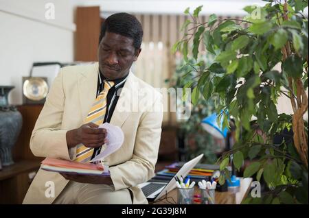 Documenti di lettura dell'uomo d'affari afro-americano concentrati in ufficio Foto Stock
