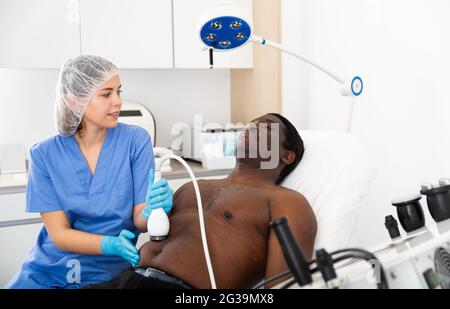 Afro uomo americano che ha cavitazione procedura in clinica di bellezza Foto Stock