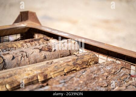 Tronchi di legno non trattati giacciono l'uno sopra l'altro in un contenitore di metallo all'esterno Foto Stock