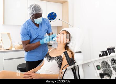 Donna che riceve iniezioni per l'aumento del labbro presso la clinica di cosmetologia Foto Stock