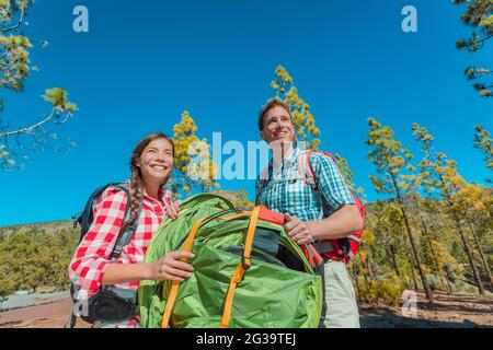 Camping coppia estate turistico stile di vita felice giovani si dispiega tenda portando l'attrezzatura per la vacanza campeggio sulla natura foresta paesaggio esterno sfondo Foto Stock