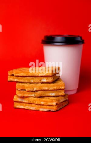 tazza bianca di caffè e tre waffle su sfondo rosso Foto Stock