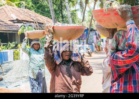 Lavoratrici indiane manuali che trasportano carichi pesanti sulle loro teste in cantiere, Agonda, Goa, India Foto Stock