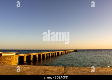 Vecchio molo in legno (molo) del faro di Sanganeb Reef vicino a Port Sudan, sul Mar Rosso, nel Parco Nazionale di Sanganeb, con orizzonte infinito vista mare duri Foto Stock