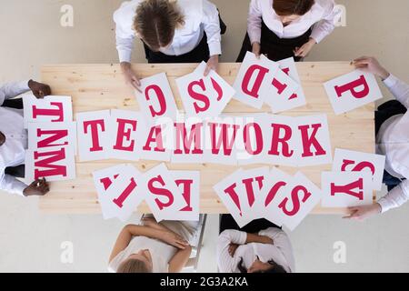 Gruppo multietnico di persone diverse che raggruppano le lettere del concetto di cooperazione di lavoro di squadra Foto Stock