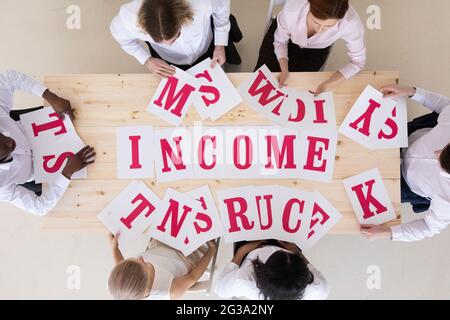 Gruppo multietnico di persone diverse che mettono le lettere reddito lavoro di squadra concetto di cooperazione Foto Stock