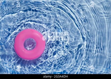 Anello di galleggiamento della piscina rosa che galleggia in una rinfrescante piscina blu. Vista dall'alto Foto Stock