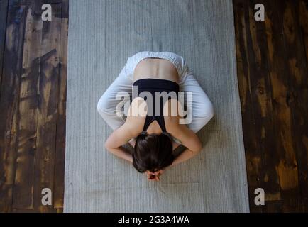 Giovane donna attraente in baddha konasana pongono contro il piano win Foto Stock