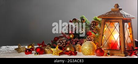 Composizione di Natale della lanterna ornamenti colorati sfere stelle candele e Abete rami sulla neve Foto Stock