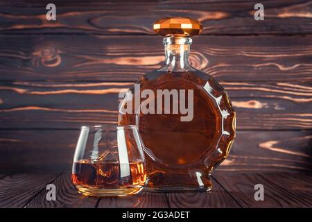 Bicchiere e bottiglia di whisky. Decanter con cognac su un tavolo di legno marrone scuro. Brandy, bourbon. Bevanda alcolica forte. Rum, scotch. Ancora vita in un RU Foto Stock