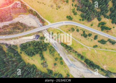 Vista aerea delle montagne in autunno. La strada tortuosa lungo il fiume. Splendido paesaggio naturale. Ponte sul fiume Prut vicino al villaggio Tatariv, Foto Stock