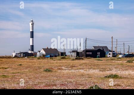 Cottage di legno con il nuovo Lighhouse in lontananza sulla Dungeness Estate, Romney Marsh, Kent, Inghilterra, UK. Foto Stock