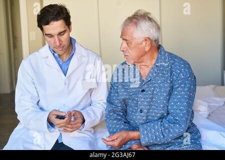 Un infermiere geriatrico controlla il livello di zucchero nel sangue di un anziano affetto da diabete sul dispositivo di misurazione Foto Stock