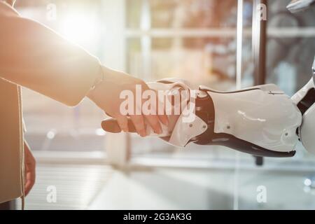 vista ritagliata di uomini d'affari e robot che scuotono le mani Foto Stock