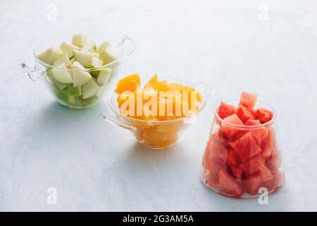 Pezzi di frutta tropicale in un bicchiere. Fette di arancia, Apple, fette di cocomero in recipiente di vetro. Agrumi Foto Stock