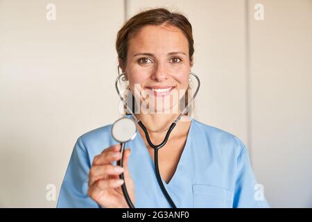 Giovane donna come medico amichevole con stetoscopio o come infermiera nella professione d'infermiera Foto Stock