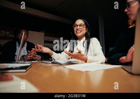 Ritratto di una giovane donna d'affari sorridente che ha discusso con il suo collega in riunione Foto Stock