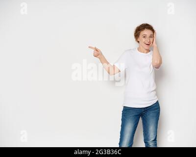 Una donna anziana in una t-shirt bianca mostra il dito sul lato Copy Space Foto Stock