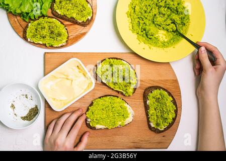 Antipasto con avocado. Il processo di preparazione dei panini per colazione, pranzo e cena. Concetto di cibo sano. Crostini di cereali marroni con Foto Stock
