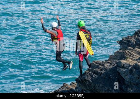 I vacanzieri saltano dalle rocce costellando con una guida su Towan Head a Newquay in Cornovaglia. Foto Stock