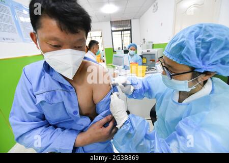 Fuyang City, Cina. 15 giugno 2021. Un operatore sanitario somministra una dose di vaccino Sinopharm COVID-19 ad un uomo. Presso la clinica di vaccinazione del centro di assistenza sanitaria della comunità di Gulou, il personale medico si prepara a vaccinare i cittadini con il vaccino inattivato del gruppo Sinopharm covid-19. Secondo la Commissione nazionale per la protezione della salute della Cina, al 14 giugno 2021, 31 province (regioni autonome e comuni) e il corpo di produzione e costruzione Xinjiang ha riferito 904 milioni di 134 mila dosi di vaccino COVID-19. Credit: SOPA Images Limited/Alamy Live News Foto Stock