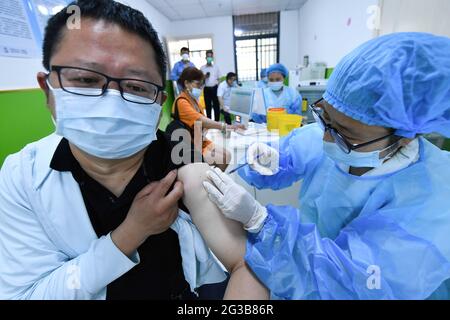 Fuyang City, Cina. 15 giugno 2021. Un operatore sanitario somministra una dose di vaccino Sinopharm COVID-19 ad un uomo. Presso la clinica di vaccinazione del centro di assistenza sanitaria della comunità di Gulou, il personale medico si prepara a vaccinare i cittadini con il vaccino inattivato del gruppo Sinopharm covid-19. Secondo la Commissione nazionale per la protezione della salute della Cina, al 14 giugno 2021, 31 province (regioni autonome e comuni) e il corpo di produzione e costruzione Xinjiang ha riferito 904 milioni di 134 mila dosi di vaccino COVID-19. Credit: SOPA Images Limited/Alamy Live News Foto Stock