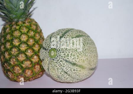 Ananas e melone su sfondo bianco. Foto Stock