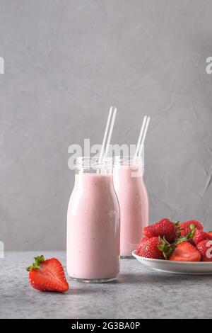 Tradizionale ayurvedico sano indiano fragola lassi o frullato in due bottiglia su sfondo grigio. Formato verticale. Foto Stock