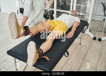 Uomo sdraiato sul lettino durante la seduta di fisioterapia Foto Stock