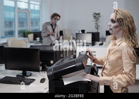 Donna d'affari Zombie che usa la macchina xerox in ufficio Foto Stock