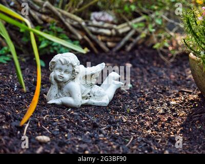 Un piccolo angelo statua si trova a terra e ci guarda Foto Stock