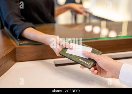 Mano della receptionist femminile che prende il passaporto del cliente dell'hotel Foto Stock