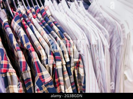 Camicie a manica lunga appese su appendiabiti in un negozio di abbigliamento. Primo piano Foto Stock