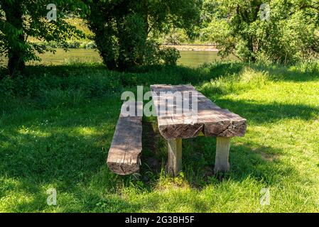 Tavolo lungo con panchine in legno in un prato vicino al fiume. Foto Stock