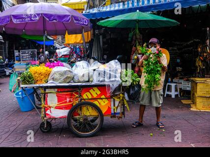 Un venditore di strada maschile organizza i suoi prodotti sul suo carrello a Chinatown, Bangkok, Thailandia Foto Stock