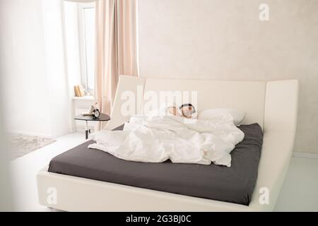 Giovane donna brunetta che dormiva a letto al mattino Foto Stock