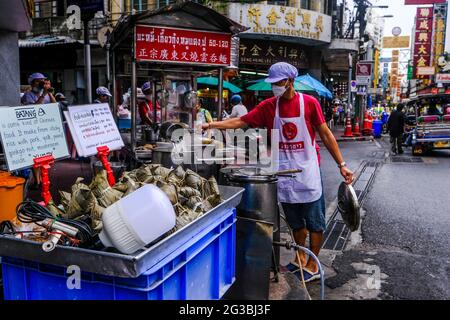 Un venditore maschile di cibo di strada lavora presso il suo stand di cibo a Chinatown, Bangkok, Thailandia. Foto Stock