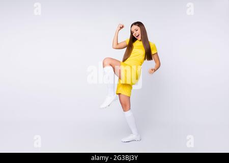 Foto a corpo pieno di allegra fan lady di sport pazzo solleva pugni sostegno gambe giocatori indossare squadra di calcio preferita giallo uniforme t-shirt pantaloncini lunghi calzini Foto Stock