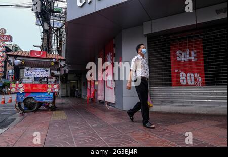 Un uomo cammina davanti a un negozio che fa pubblicità agli sconti di vendita a Chinatown, Bangkok, Thailandia. Foto Stock