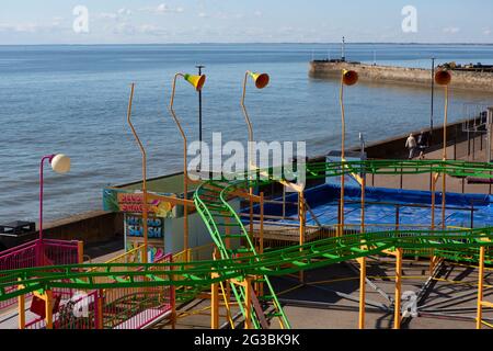 Il giro sulle montagne russe vuote e chiuse alla fiera di divertimento a Bridlington nel nord dello Yorkshire con una ruota panoramica sullo sfondo Bridlington è una costa Foto Stock