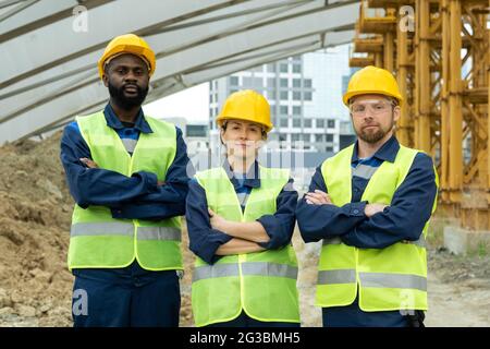 Tre ingegneri o costruttori di successo in hardhats e uniforme Foto Stock