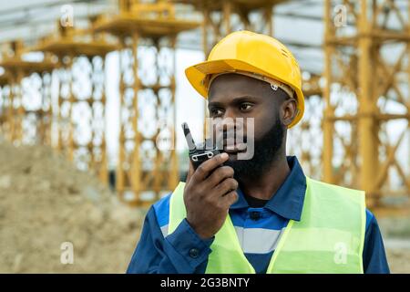 Ingegnere maschile o caposquadra di etnia africana utilizzando walkie-talkie Foto Stock