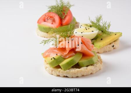 Pane di riso croccante, avocado, fette di uova sode, salmone, pomodori e aneto fresco Foto Stock