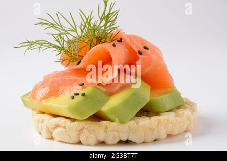 Pane di riso croccante, avocado, fette di salmone e aneto fresco Foto Stock