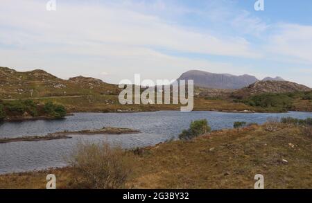 Caratteristiche colline, brughiere e laghi nelle Highlands scozzesi lungo la panoramica rotta della costa settentrionale 500 che inizia e si snoda a Inverness Foto Stock