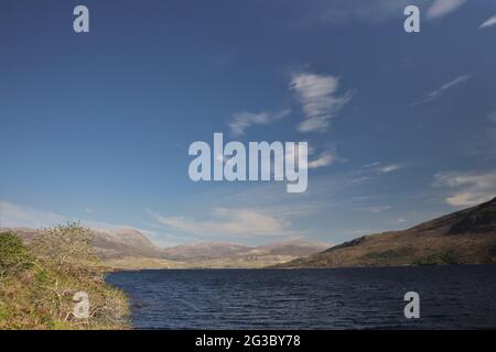 Caratteristiche colline, brughiere e laghi nelle Highlands scozzesi lungo la panoramica rotta della costa settentrionale 500 che inizia e si snoda a Inverness Foto Stock