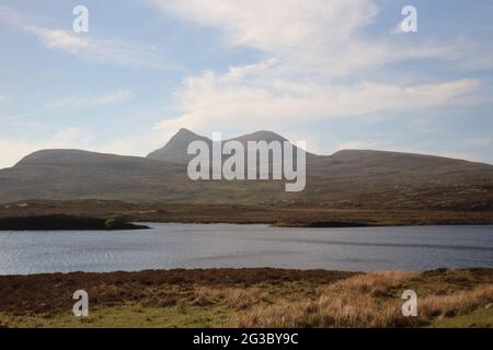 Caratteristiche colline, brughiere e laghi nelle Highlands scozzesi lungo la panoramica rotta della costa settentrionale 500 che inizia e si snoda a Inverness Foto Stock